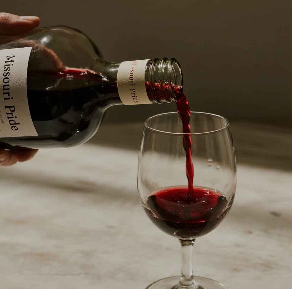 bottles and glasses of Sainte Genevieve wines with vineyard